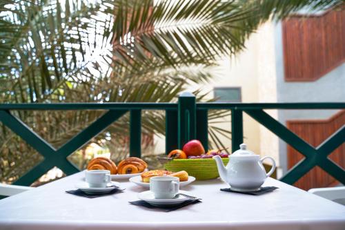 a table with a bowl of fruit and two cups of coffee at Branco Sea Holiday Apartments in Santa Maria
