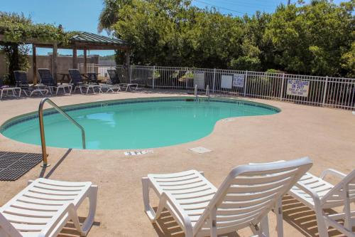 a swimming pool with chairs and a group oficans at Sunset Retreat in Folly Beach