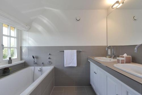 a bathroom with a tub and two sinks and a mirror at Kairem Ingiwai 22c in Keitum