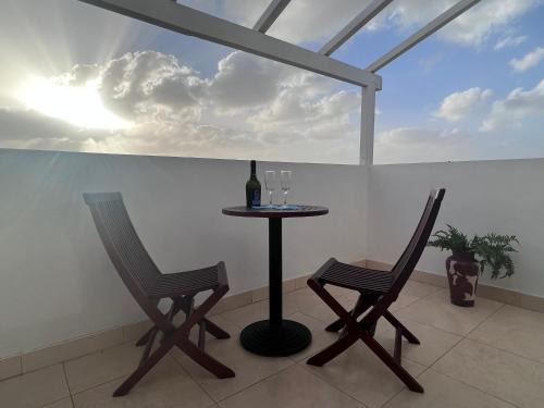 a table with two chairs and a bottle of wine at Branco Suites - Rooms & Holiday Apartments in Santa Maria