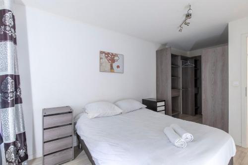 ein Schlafzimmer mit einem weißen Bett mit zwei Handtüchern darauf in der Unterkunft Le Lagon Parking Un Séjour à Part in Longeville-lès-Metz