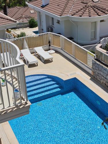 a swimming pool with two lounge chairs next to a house at Villa Rana The Royal Links Sarigerme in Ortaca