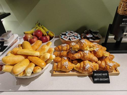 een tafel met verschillende soorten brood en fruit bij Alkimia Apartments in Ferrara