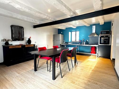 une cuisine avec une table noire et des chaises rouges dans l'établissement La Longère, à Guilliers