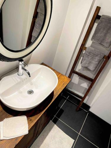 une salle de bain avec un lavabo et un miroir sur un comptoir dans l'établissement La Longère, à Guilliers