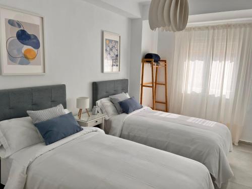 2 camas en un dormitorio con blanco y azul en Victoria Centro 34, en Puerto Real