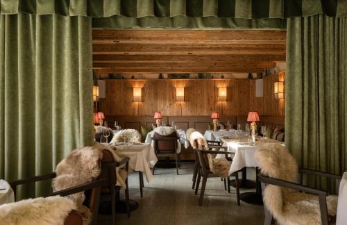 a dining room with tables and chairs and curtains at Hotel GRACE LA MARGNA ST MORITZ in St. Moritz