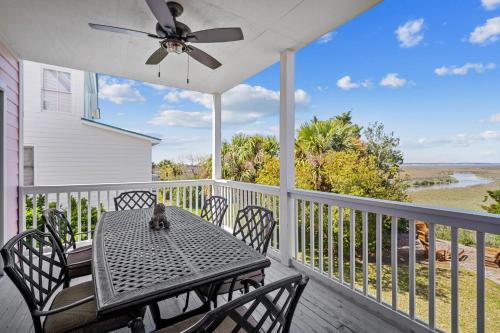 a table and chairs on a porch with a ceiling fan at Beach Access - Golf Cart Included - Views of the Marsh and Harbor River - Sleeps 10 in Harbor Island