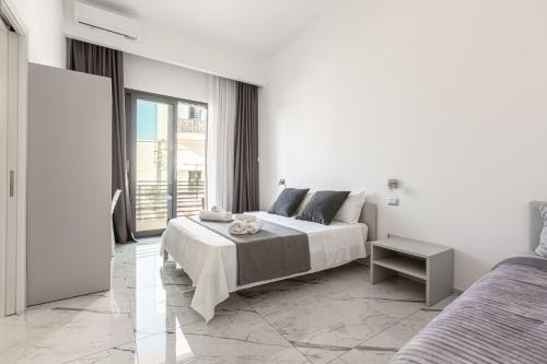a white bedroom with a bed and a large window at La Corte dei Pozzi in Sannicola