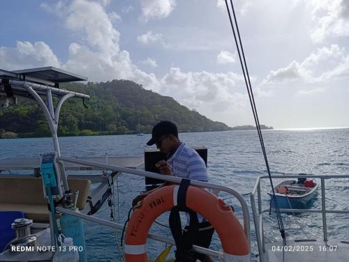 a man sitting on a boat in the water at Hostal Portobelo in Portobelo