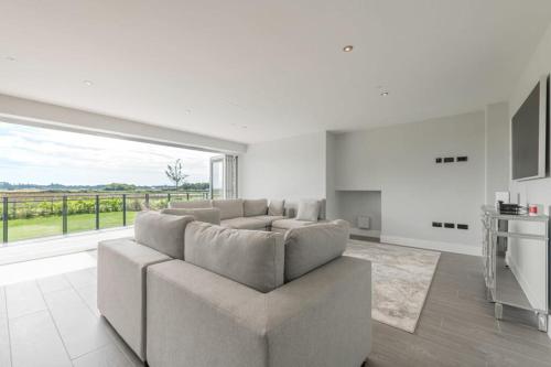 a living room with a couch and a large window at Modern 5 Bedroom Luxury Home with Sea Views and Hot Tub in North Hayling