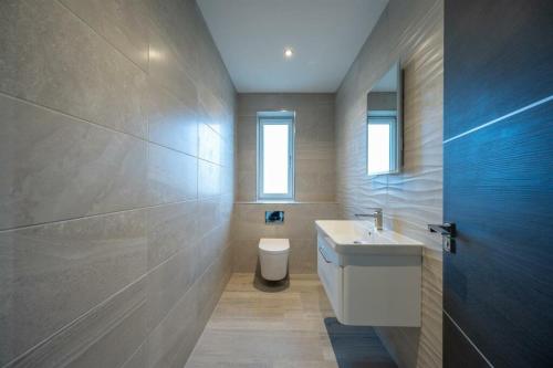 a bathroom with a white sink and a toilet at Modern 5 Bedroom Luxury Home with Sea Views and Hot Tub in North Hayling