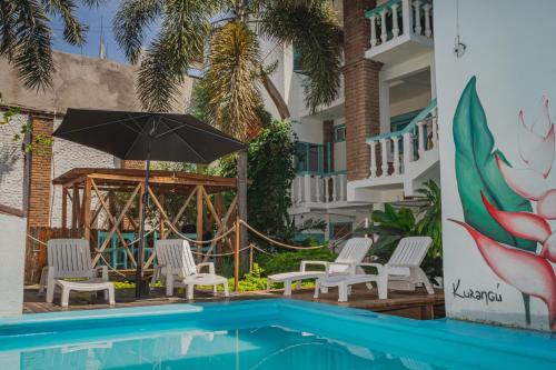 a resort with a swimming pool with chairs and an umbrella at Hotel Costa 55 Puerto Escondido in Puerto Escondido
