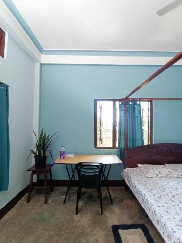 a room with a table and a bed and a table and chair at Anita Homestay in Silchar