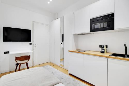 - une cuisine blanche avec une chaise et un four micro-ondes dans l'établissement Pretty Studio in Paris, à Paris