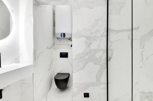 La salle de bains est pourvue de murs en marbre blanc et de toilettes. dans l'établissement Pretty Studio in Paris, à Paris