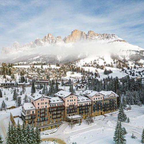 a resort in the snow with mountains in the background at Residence Grand Hotel Carezza in Nova Levante