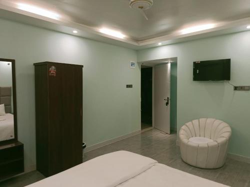 库克斯巴扎Sun Oasis Resort的一间卧室，配有一张床、一把椅子和一台电视机