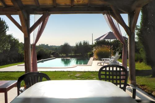 une table et des chaises sous un pavillon avec une piscine dans l'établissement Villa charmante à Issac avec piscine privée, à Issac
