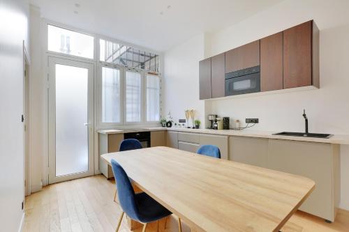 une cuisine avec une table en bois et des chaises bleues dans l'établissement Beautiful 2 BDR Duplex in Paris, à Paris