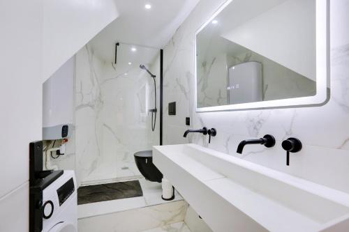 une salle de bain blanche avec un lavabo et une douche dans l'établissement Beautiful 2 BDR Duplex in Paris, à Paris
