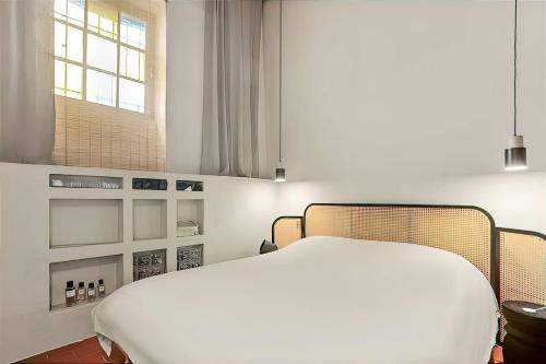 une chambre avec un lit blanc et une fenêtre dans l'établissement Maison Gaï Soleil, à Grimaud