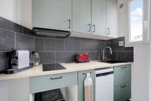 une cuisine avec des armoires blanches et un appareil rouge dans l'établissement Studio Lumineux au pied du RER A - Avec ascenseur, à Vincennes