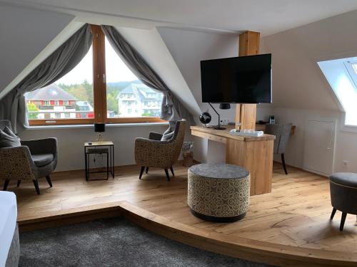 a living room with a large window and a tv at Hotel Sonne Garni in Hinterzarten
