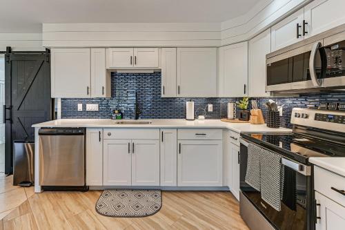 a kitchen with white cabinets and stainless steel appliances at 1 Mi to Bonita Beach Park Chic Canal-Front Home! in Bonita Springs