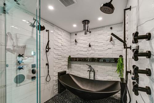 a bathroom with a black tub and a glass shower at 1 Mi to Bonita Beach Park Chic Canal-Front Home! in Bonita Springs
