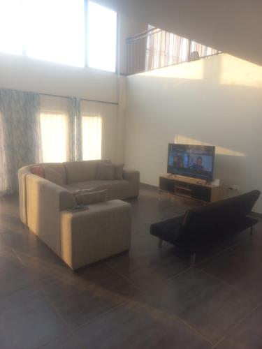 Una sala de estar con un sofá y un televisor. en Bella Cosa botique hotel, en Southbroom