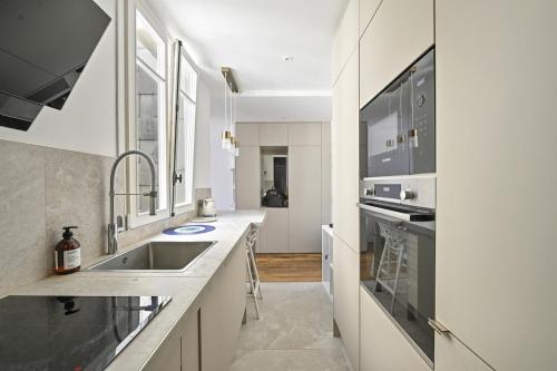 une cuisine blanche avec un évier et un comptoir dans l'établissement 2 room Apartment - 16th, à Paris