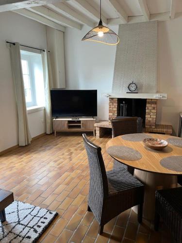 a living room with a table and a television at Maison chaleureuse et conviviale in La Caillaudière