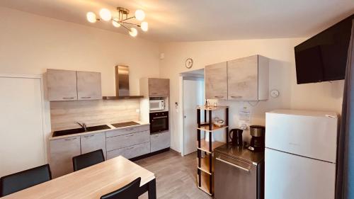 une cuisine avec une table et un réfrigérateur blanc dans l'établissement petite maison proche mer, à Notre-Dame-de-Monts