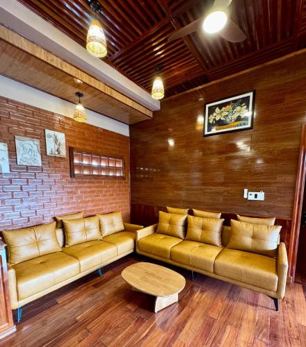 a living room with brown leather couches and a table at Golden Topaz Phu Quoc Resort in Phu Quoc