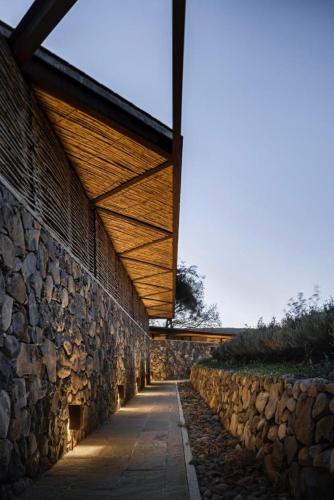 a building with a stone wall and a wooden roof at Rancho el Divisadero in La Cañada