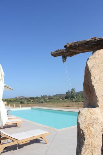 una piscina con tumbonas junto a una roca en Cantos e Sonos Charming Guest House, en Ardali