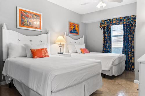 2 bedden in een slaapkamer met witte lakens en oranje kussens bij Marvelous Oceanfront 12th Floor 3BR Retreat at The WyndhamOcean Walk Resort in Daytona Beach