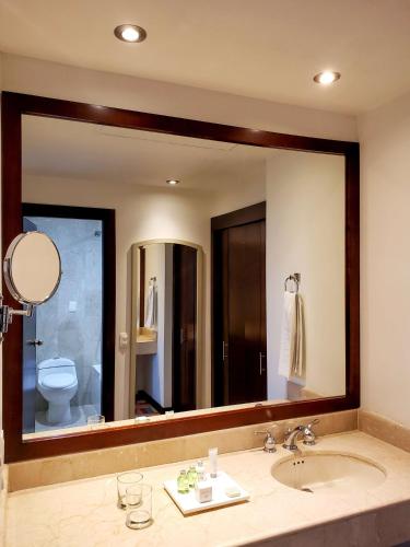 a bathroom mirror with a sink and a toilet at NH Cali Royal in Cali