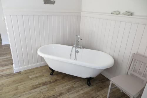 a white bath tub in a bathroom with a chair at Ferienhaus AM ALTEN HAFEN HOOKSIEL in Wangerland