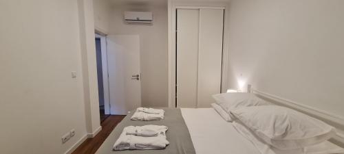 a white bedroom with two towels on a bed at Montanha a Lápis in Proença-a-Nova