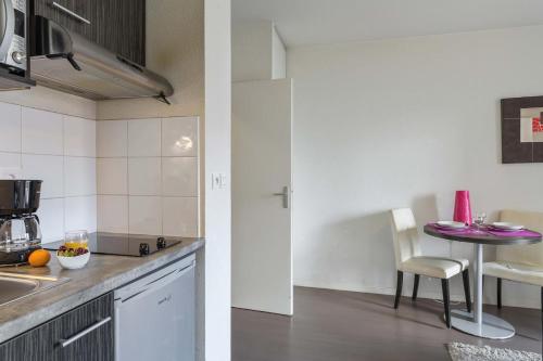 une cuisine avec un évier et une table avec une chaise dans l'établissement Le refuge urbain de Toulouse - ancien appartcity, à Toulouse