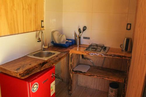 eine kleine Küche mit einer Spüle und einem roten Kühlschrank in der Unterkunft EXIT Tiny House in Pucón