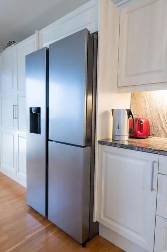 a stainless steel refrigerator in a kitchen with white cabinets at Spacious house, close to Granåsen Ski Arena! 4 beds, 2 bathrooms, free parking in Trondheim