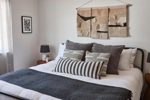 1 dormitorio con 1 cama con almohadas grises y blancas en Olive and Stone, en Templeton