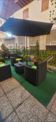 a patio with tables and an umbrella and green grass at Fiocco di Neve in Tarvisio