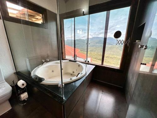 a bathroom with a tub and a window and a toilet at Refúgio de Lavras in Ouro Preto