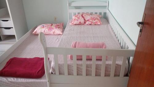 a white crib with two beds in a room at Apartamento 02 in Garopaba