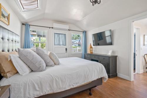 Schlafzimmer mit einem Bett mit weißer Bettwäsche und einem TV in der Unterkunft Chestnut Cottage in Paso Robles
