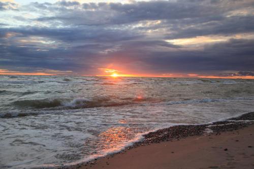 a sunset on the beach with the ocean at Sea House Dzelmes in Mazirbe